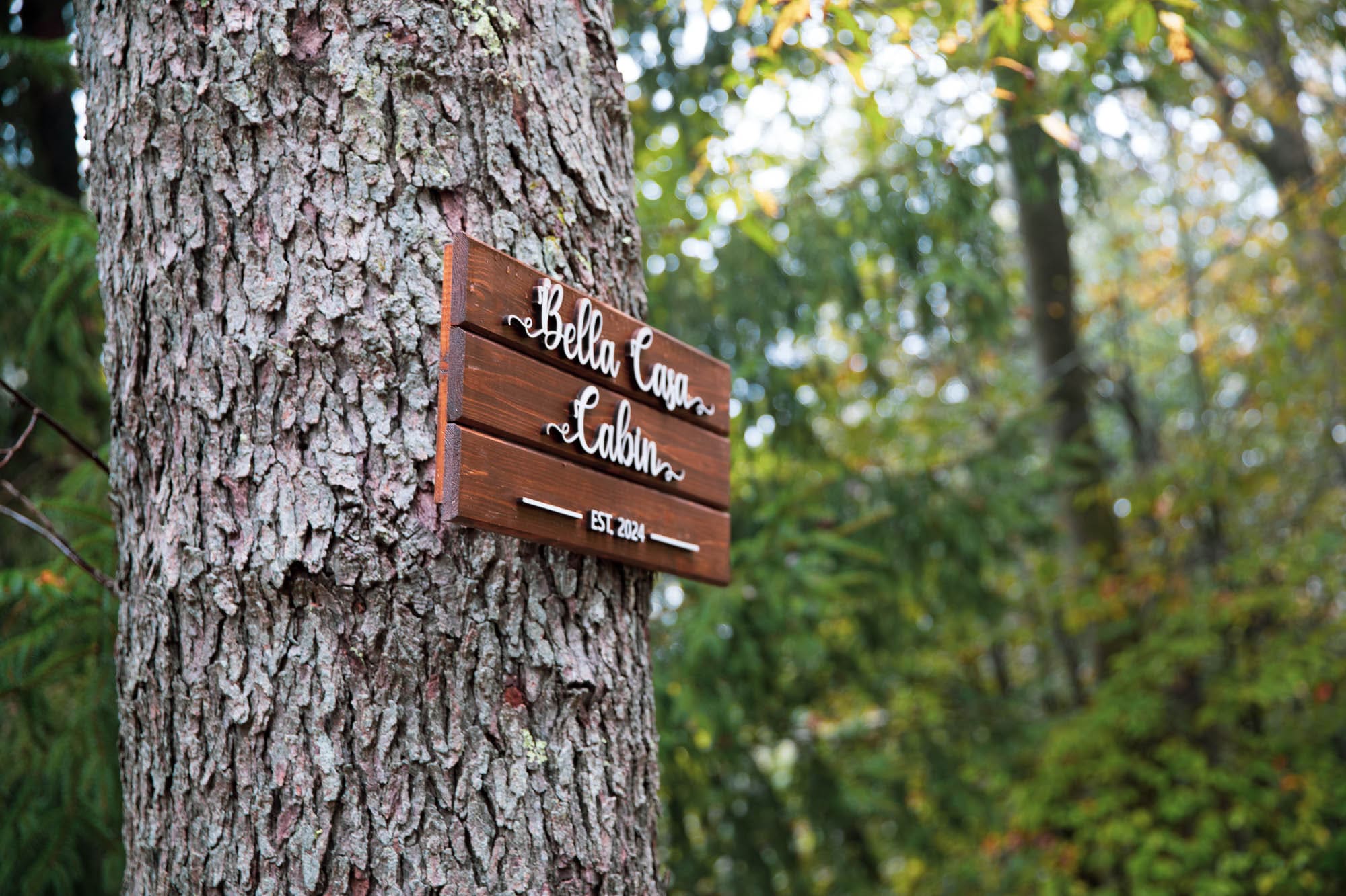 Bella Casa Cabin sign mounted on a tree at the entrance of the Pocono A-Frame retreat