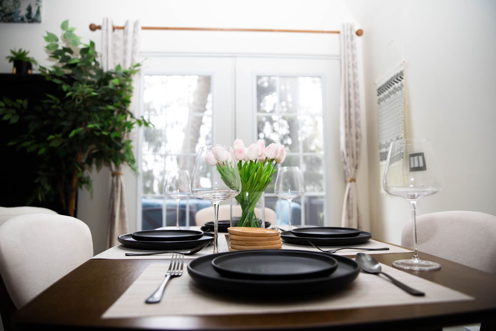 Dining table set for four with fresh tulips, beside the cabin's french doors