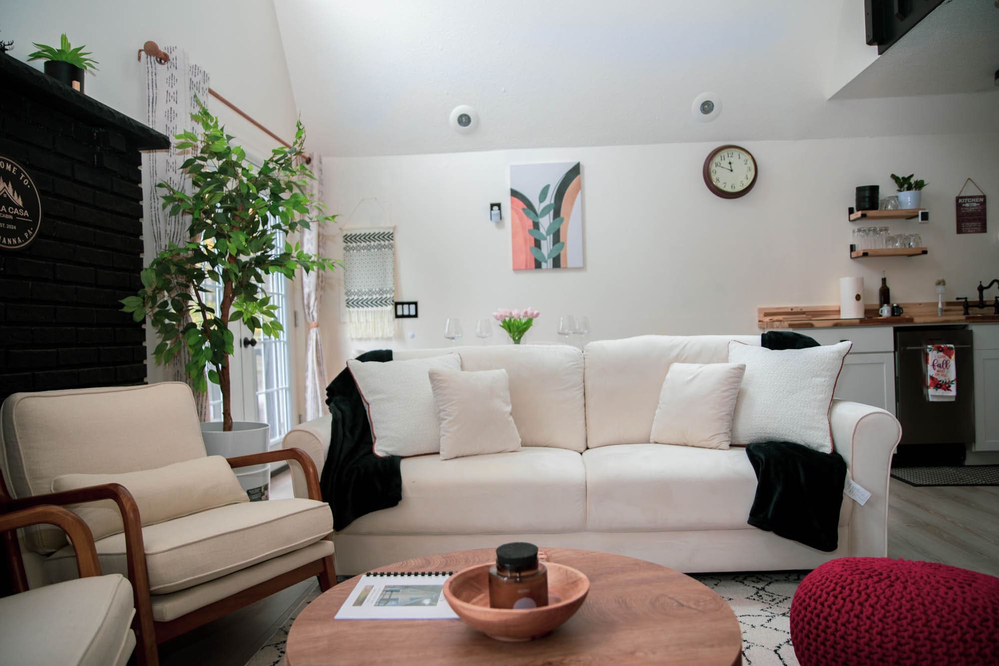Bright living room with a white sofa, indoor plants, and Bella Casa wall art