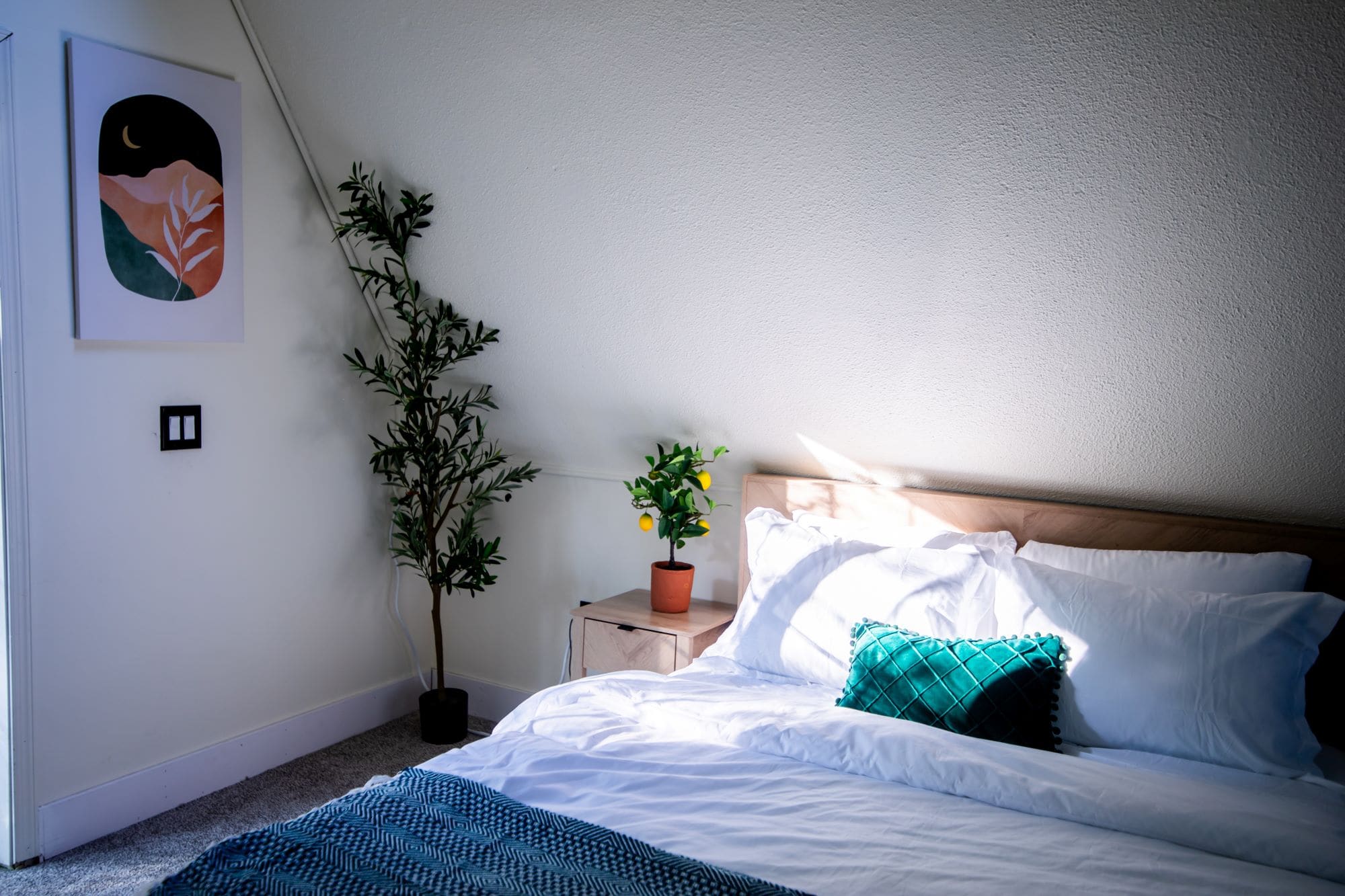 Loft bedroom with mountain artwork, queen bed, and the cabin's sloped A-Frame ceiling