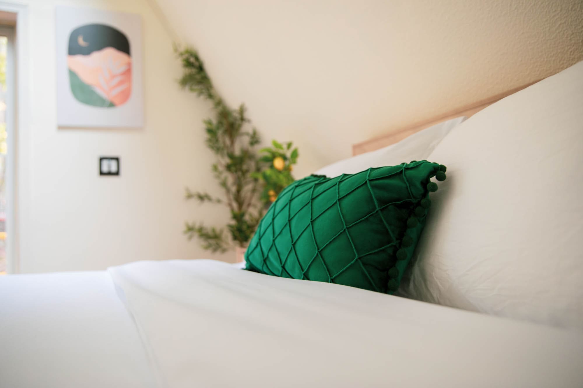 Cozy loft bedroom with crisp white linens and a velvet green pillow