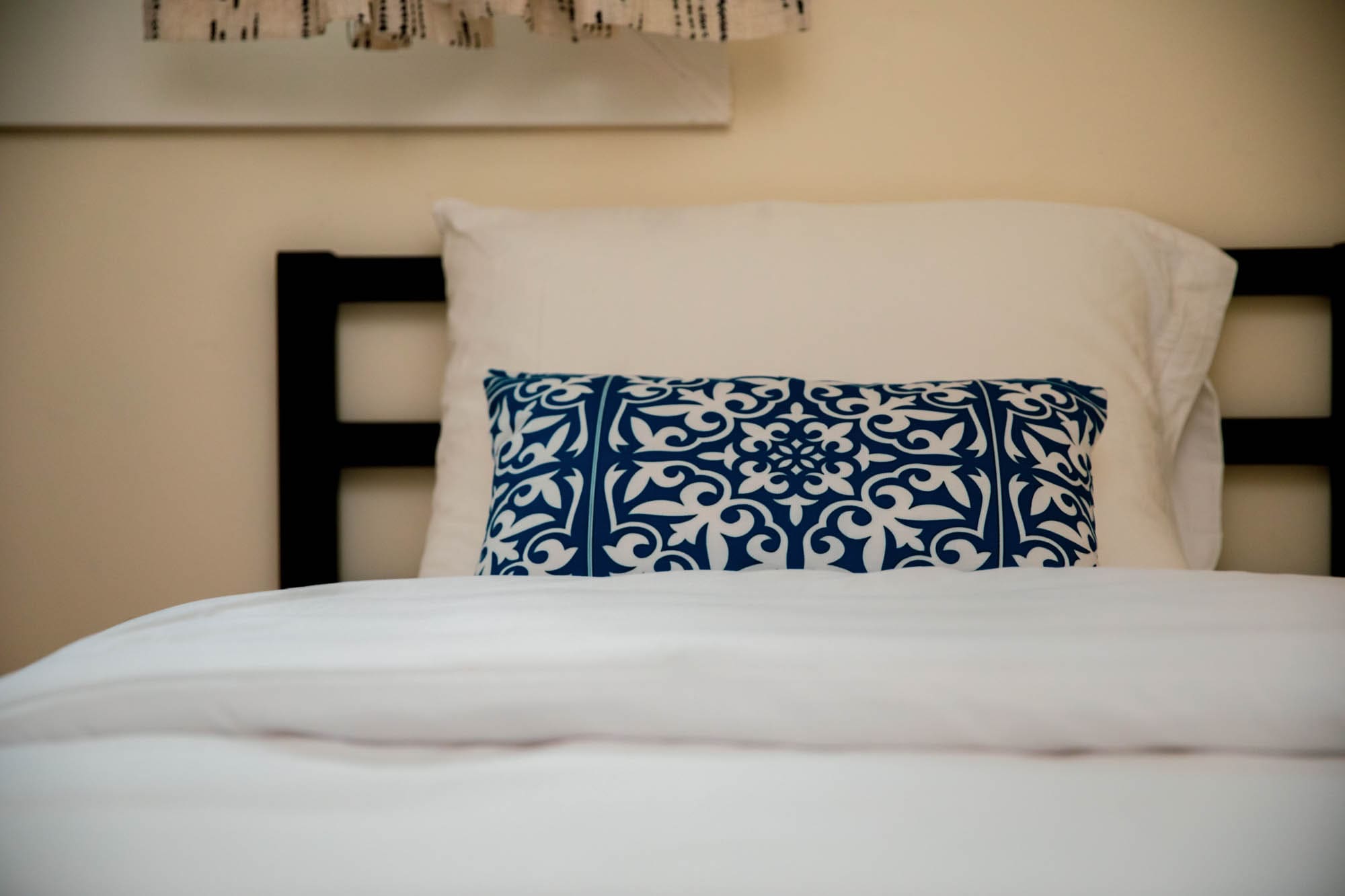 Bedroom detail with a blue and white patterned accent pillow on a queen bed