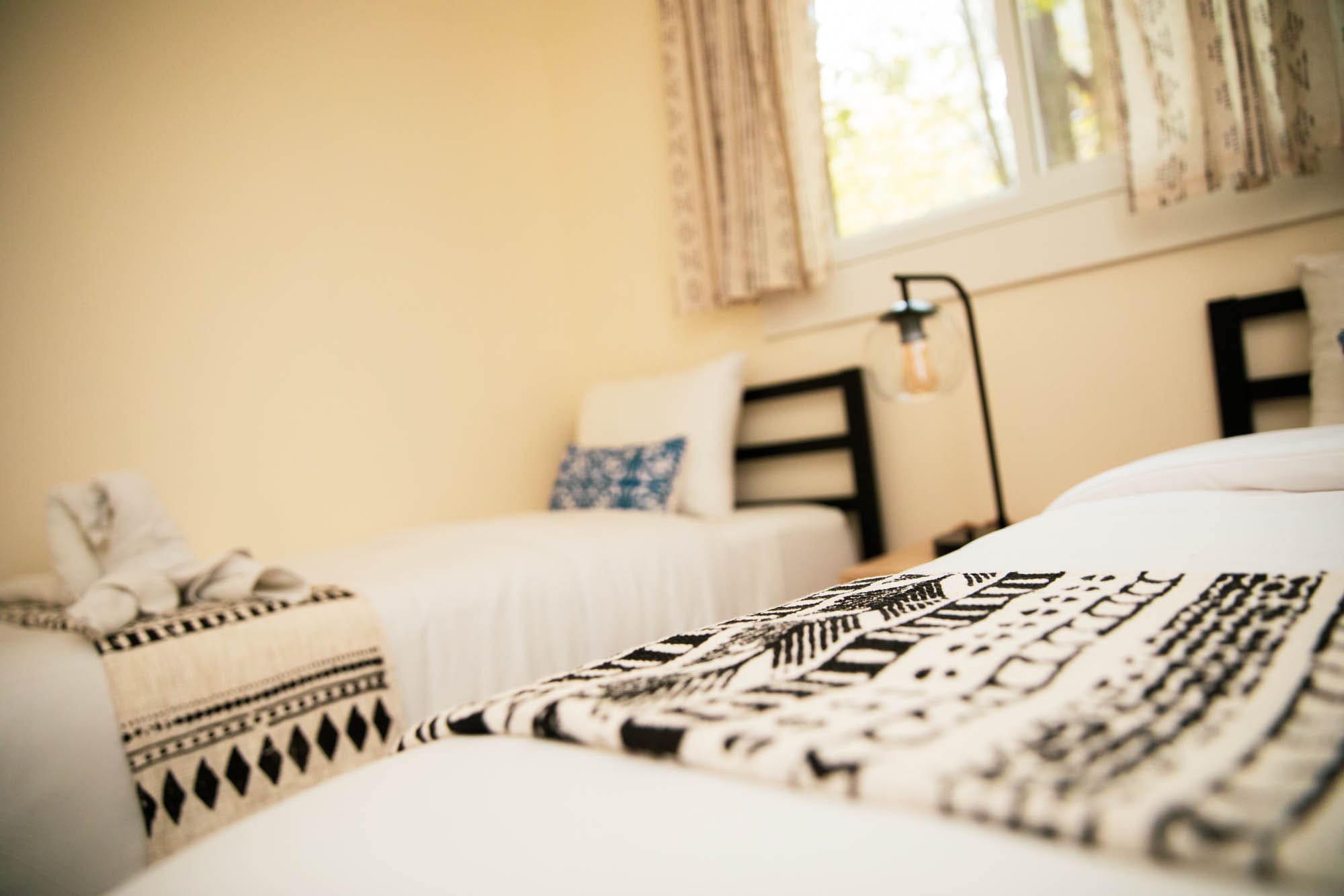 Twin beds in the second bedroom with handcrafted towel art and warm lamp lighting